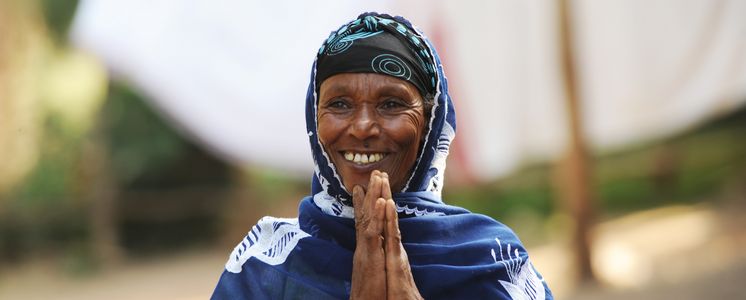 Eine äthiopische Frau faltet die Hände und lächelt dabei.