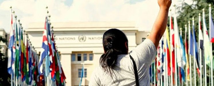 Eine südamerikanische Frau protestiert mit gestreckter Faust vor dem UN-Gebäude in Genf.