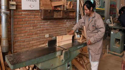Eine Frau arbeitet in einer Tischlerei an einer Maschine.