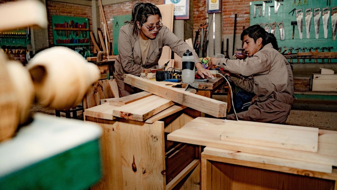 Zwei Frauen arbeiten in einer Tischlerei an einer Maschine.