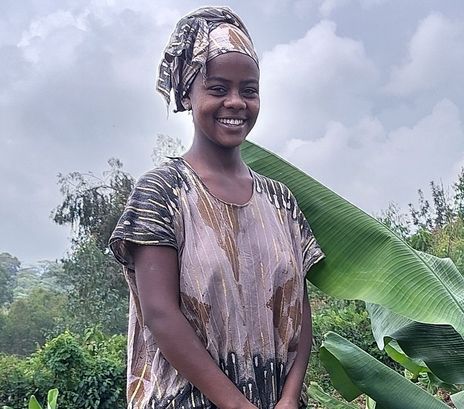 Frau bei der Feldarbeit neben einer Bananenpflanze. 