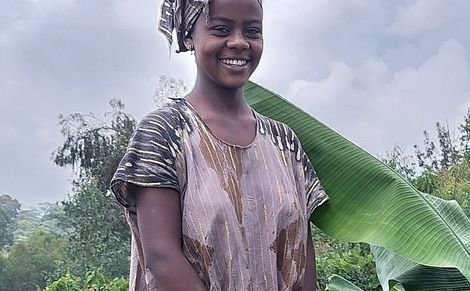 Frau bei der Feldarbeit neben einer Bananenpflanze. 