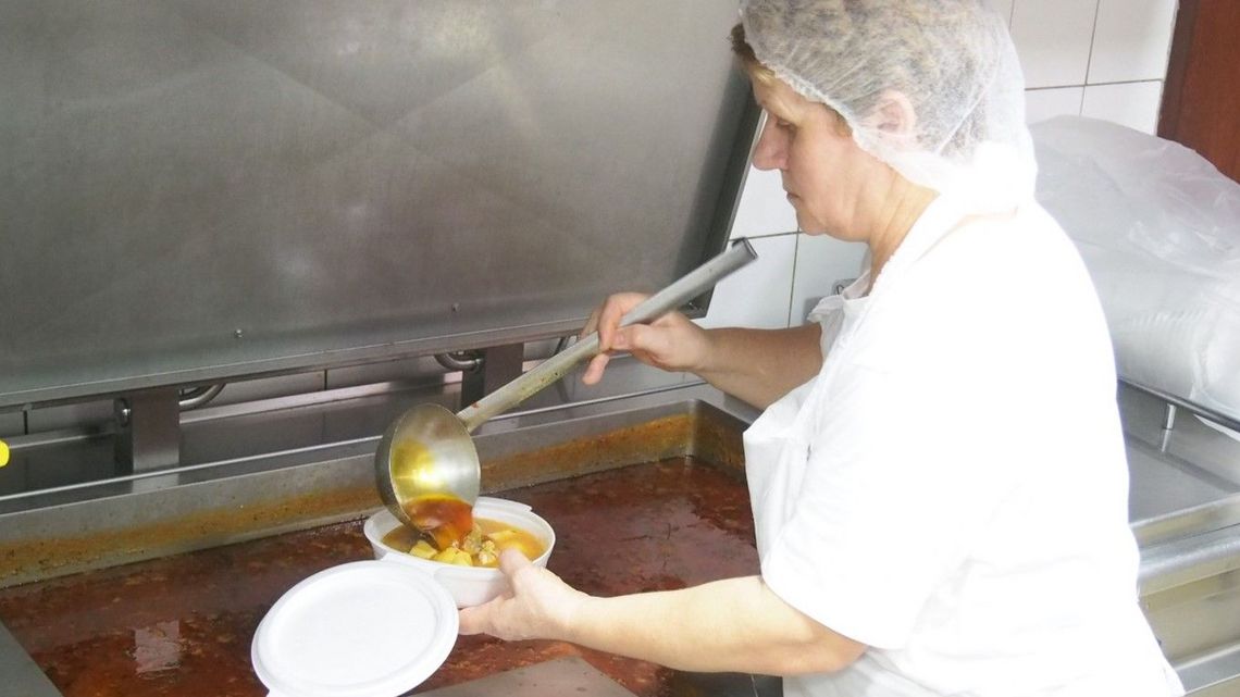 Eine Köchin befüllt einen Teller mit Essen.   